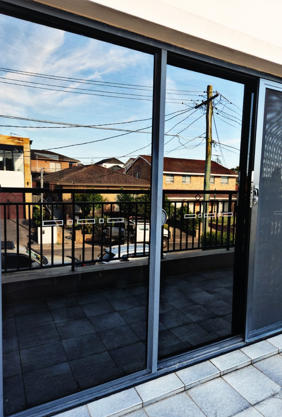 Dark tinted verandah glass panels on two-storey Sydney home by TMC Tinting — street privacy heat UV block 0449 582 777